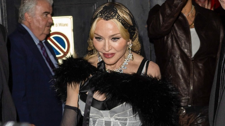 Madonna walking, wearing a furry black shawl