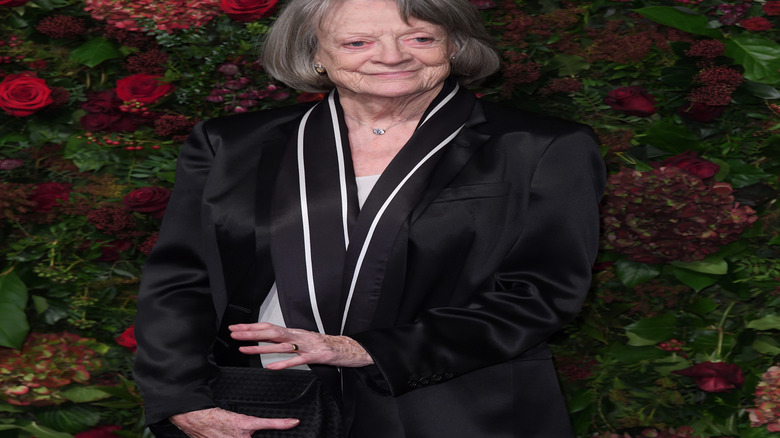 Maggie Smith in black suit against flower background