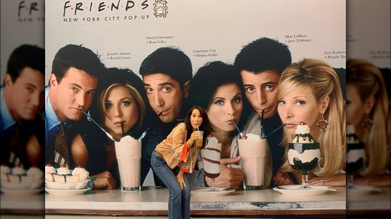 Maggie Wheeler posing with Friends billboard