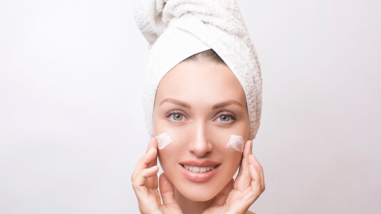 woman applying moisturizer to face