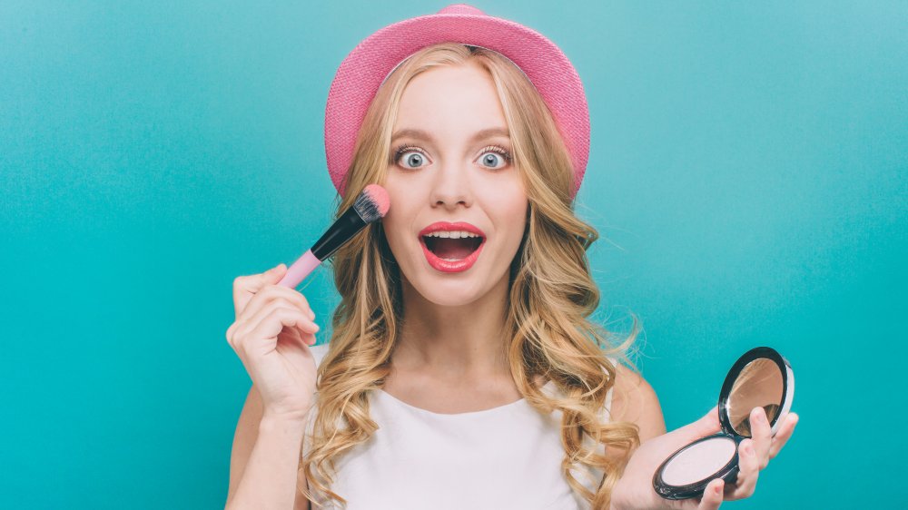 A woman applying blush on her cheek