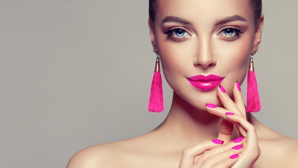 A woman wearing bright pink lipstick and nail polish