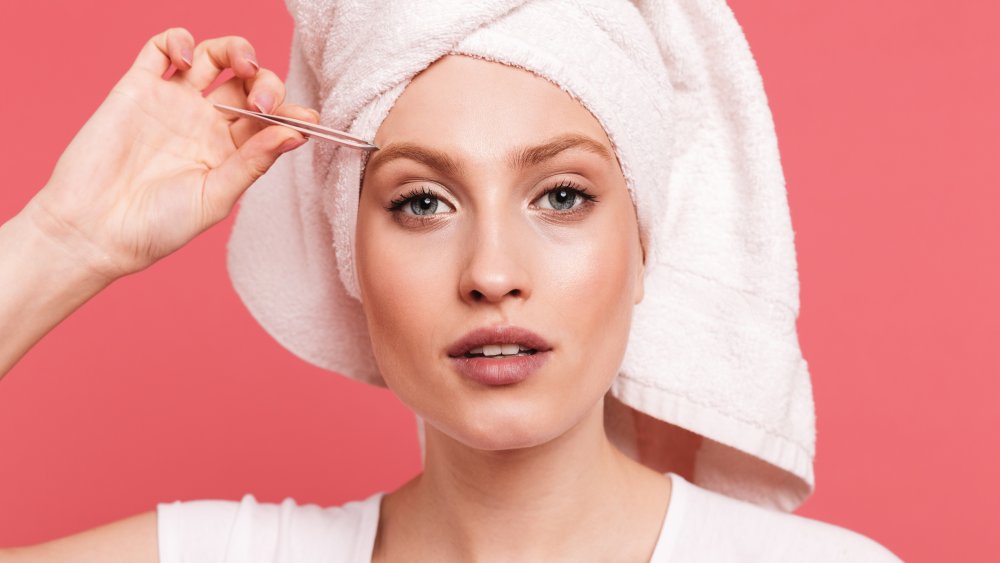 A woman plucking her eyebrows