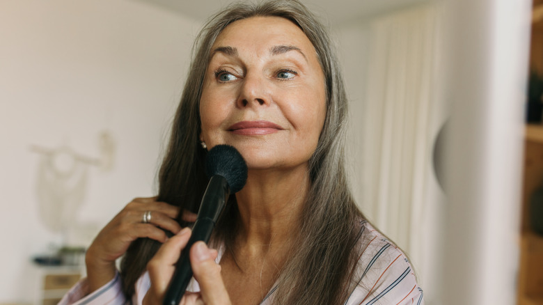 Woman applying makeup with powder brush