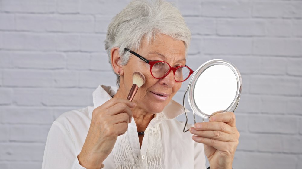 Woman applying blush in mirror