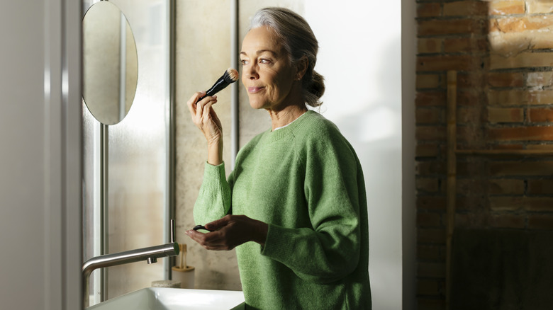 Woman applying foundation in mirror