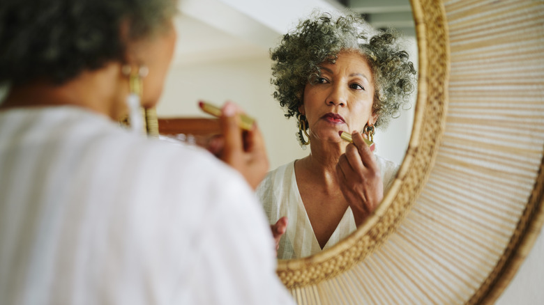 Woman applying lipstick in mirror