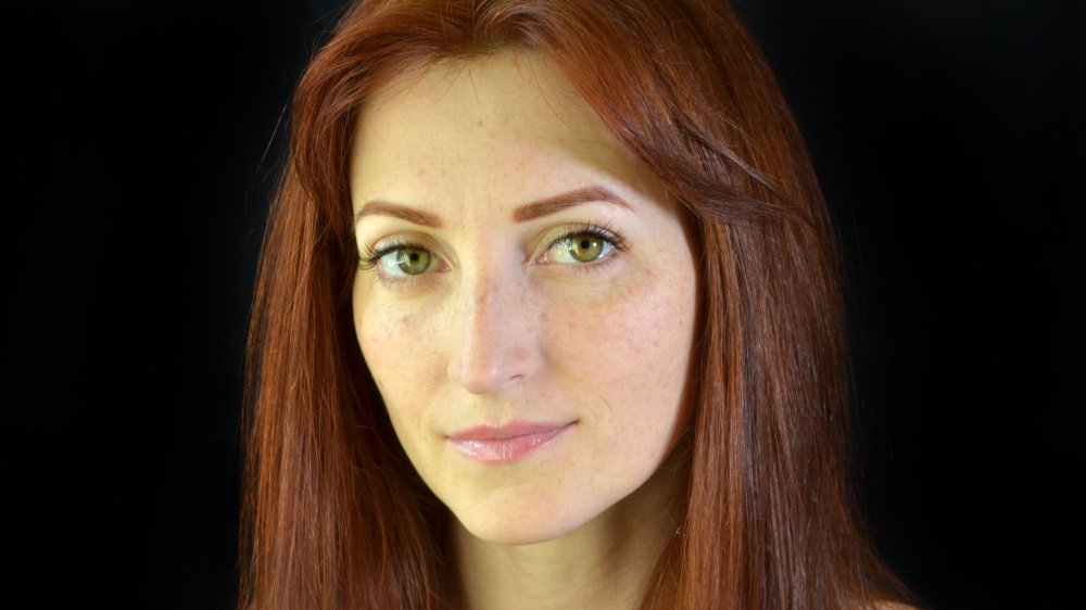 A red-headed woman wearing the fake freckle makeup trend