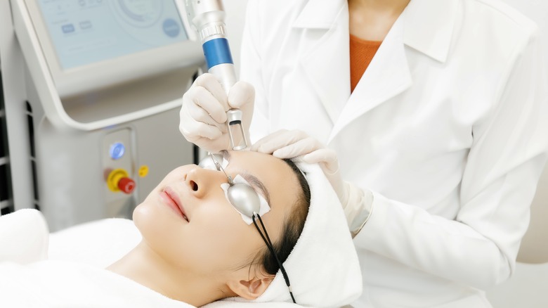 Woman wearing protective eyewear and receiving facial laser treatment