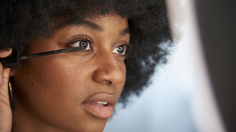 Woman applying mascara to bottom lashes