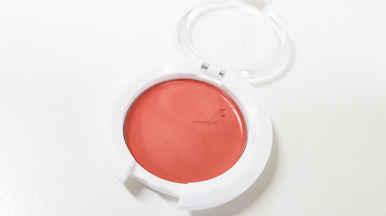 Display of white makeup compactor with rouge creamy blush