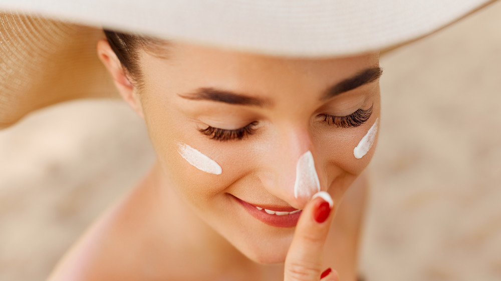 A woman applying sunscreen on her face