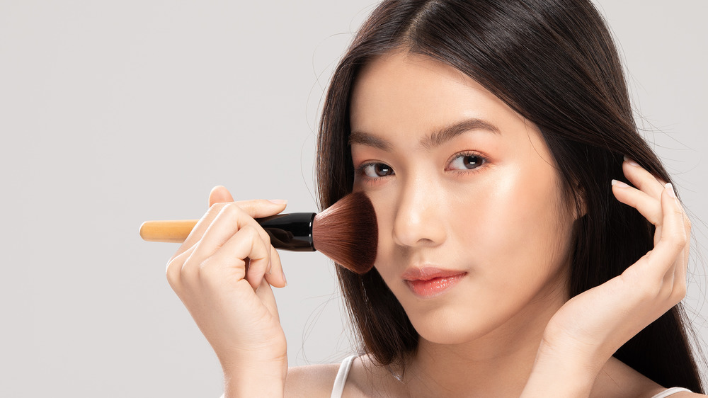 A woman holding a brush to her cheek