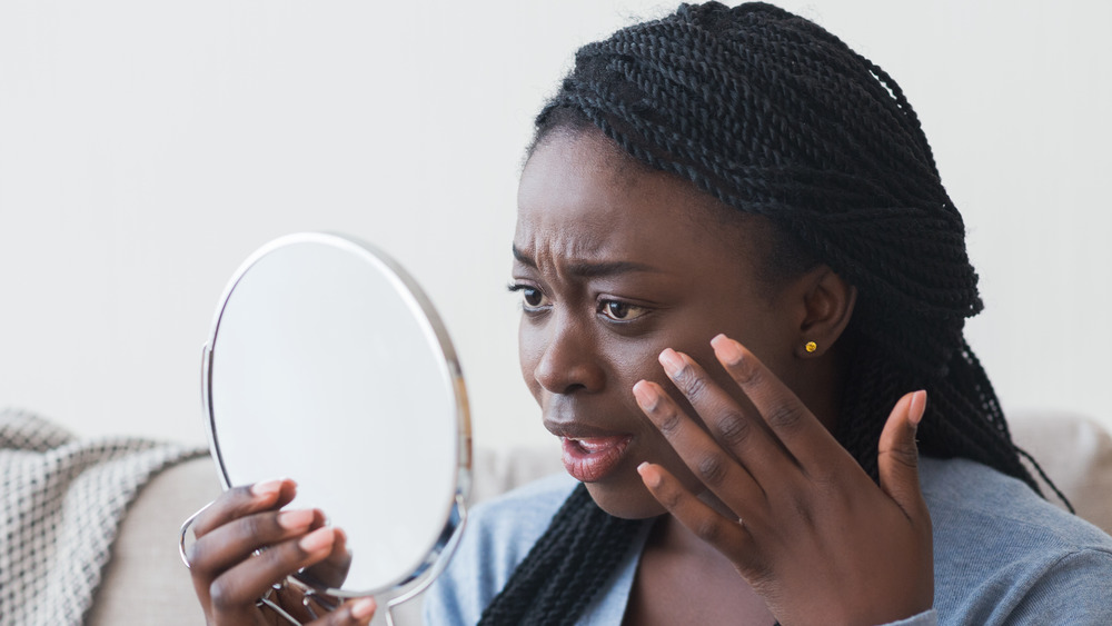 A woman looking in the mirror, concerned