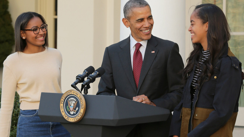 Sasha and Malia Obama standing with Barack