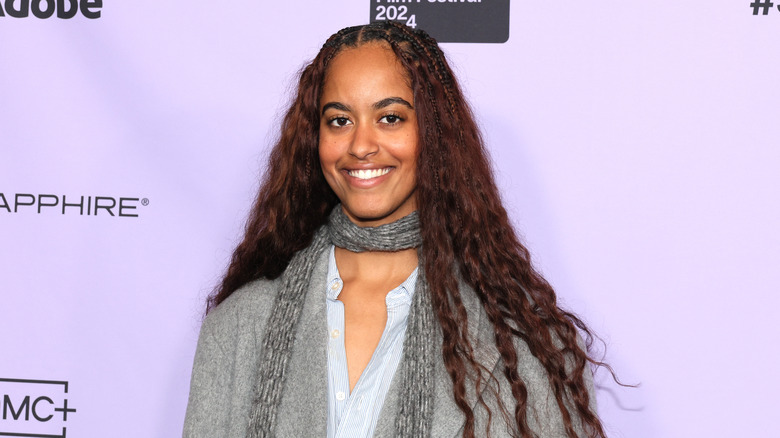 Malia Obama smiling against a purple backdrop