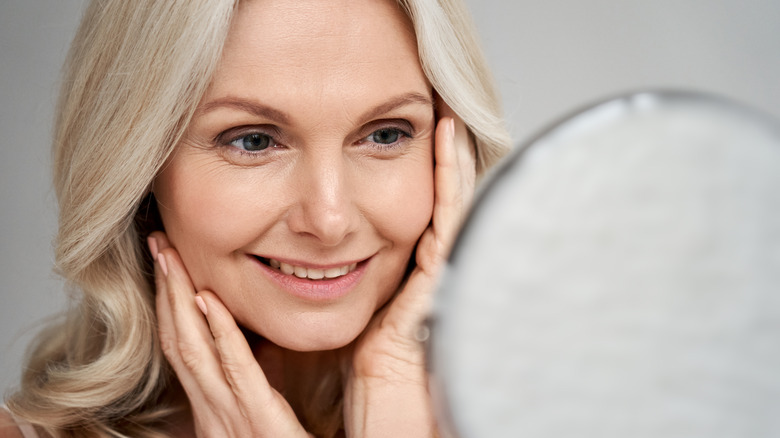 Middle aged woman smiling at a mirror