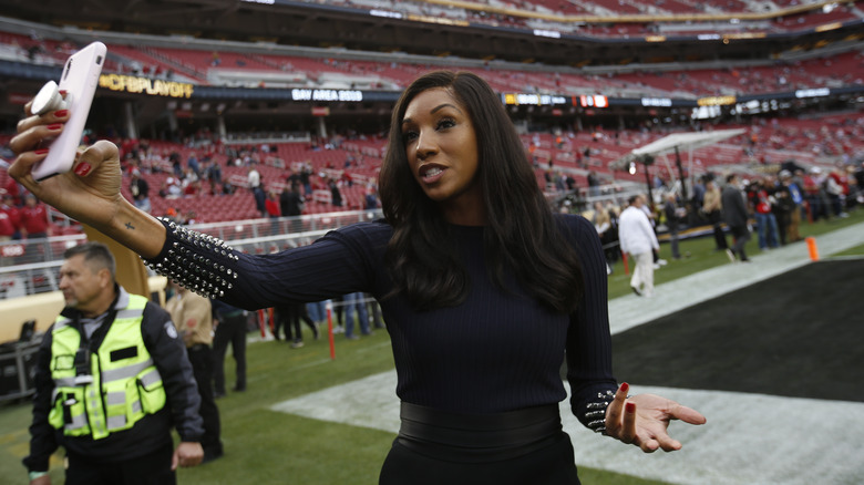 Maria Taylor speaking into her phone on a football field