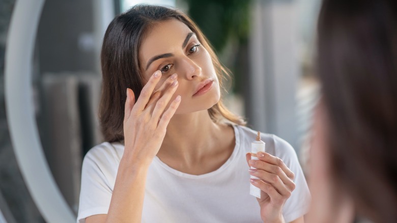 woman applying concealer to her skin