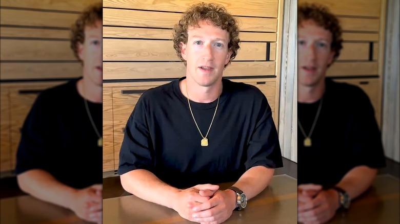 Mark Zuckerberg with curly hair in a black t-shirt and long gold chain