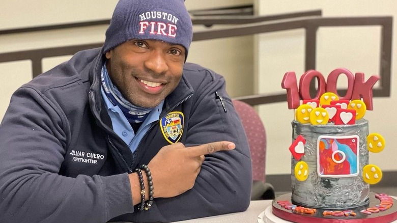 Gil Cuero smiling next to cake celebrating 100,000 Instagram followers