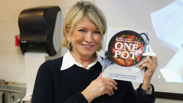 Martha Stewart smiling and holding up one of her books