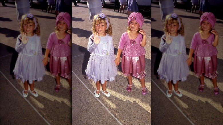 Mary Kate and Ashley Olsen as toddlers wearing pink and purple outfits