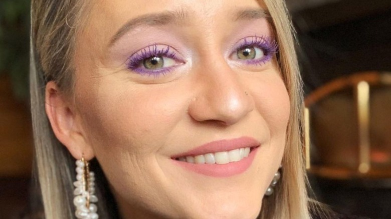 Woman with green eyes wearing purple mascara