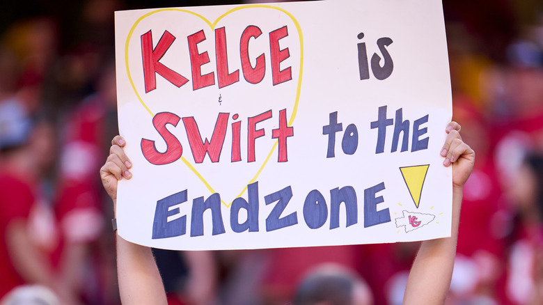 Kelce and swift sign being held up