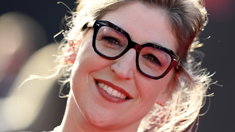 Mayim Bialik smiling in black glasses