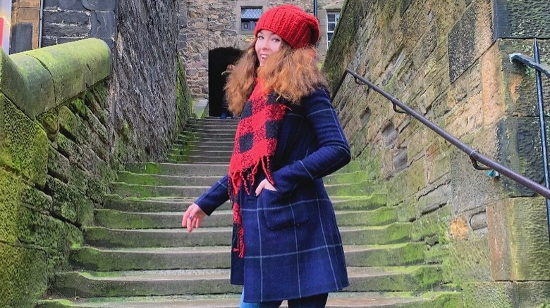 Ava Monroe smiles in red beanie and red scarf outside on stairs