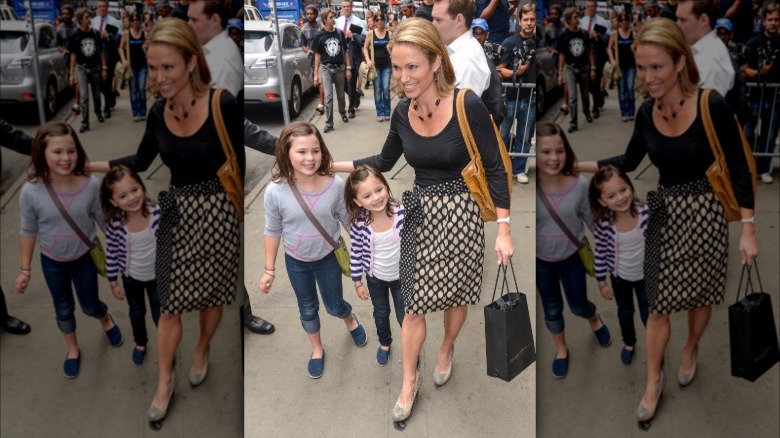 Amy Robach smiles on the sidewalk with her two daughters as children