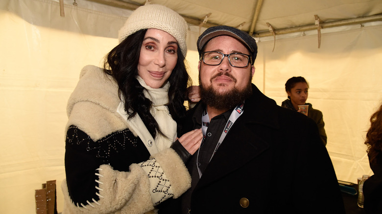 Cher and her son Chaz Bono posing for photos in a tent