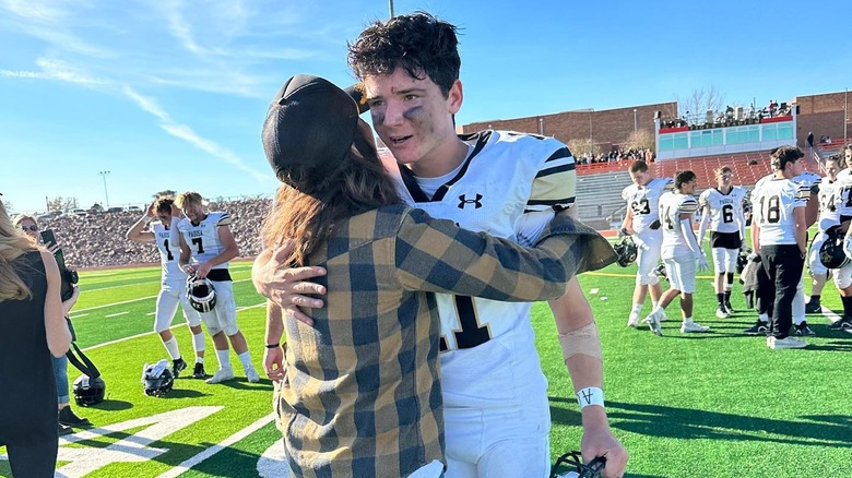 Cristi Dozier hugs her son Creede on the football field post game