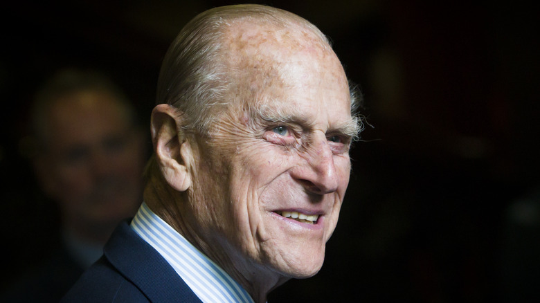 Prince Philip smiles against black background