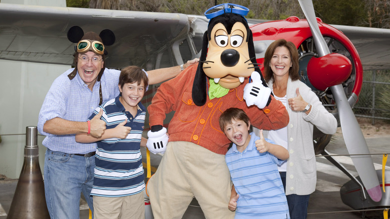 Stephen Colbert, Peter Colbert, John Colbert, and Evelyn McGee-Colbert smiling with Goofy