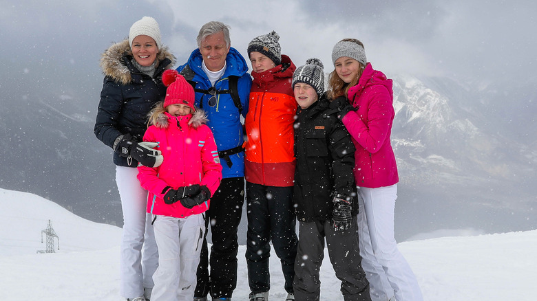 The royal family of Belgium pose in front of a mountain while it's snowing during a ski trip.