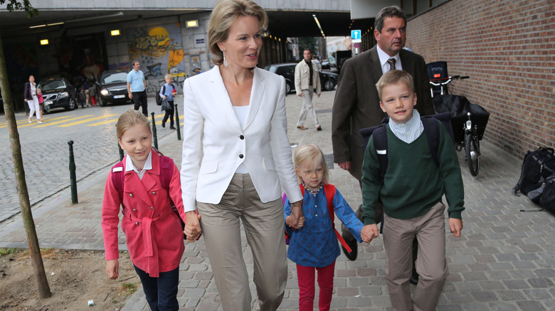 The queen of Belgium walks her young children to the first day of school.