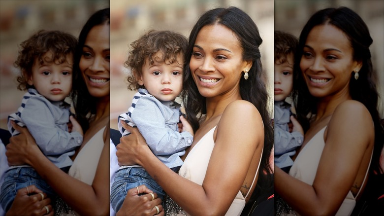 Zoe Saldaña smiling while holding her youngest son