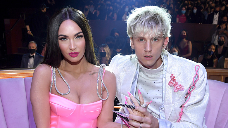 Megan Fox and MGK sit and hold hands 