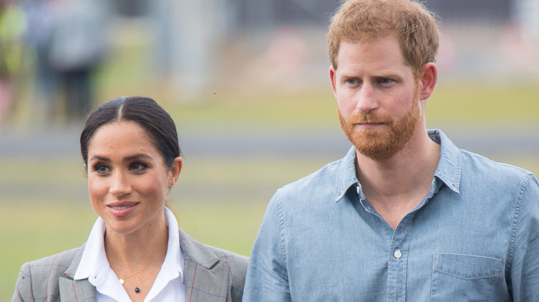 Meghan Markle with a slight smile and Prince Harry looking serious