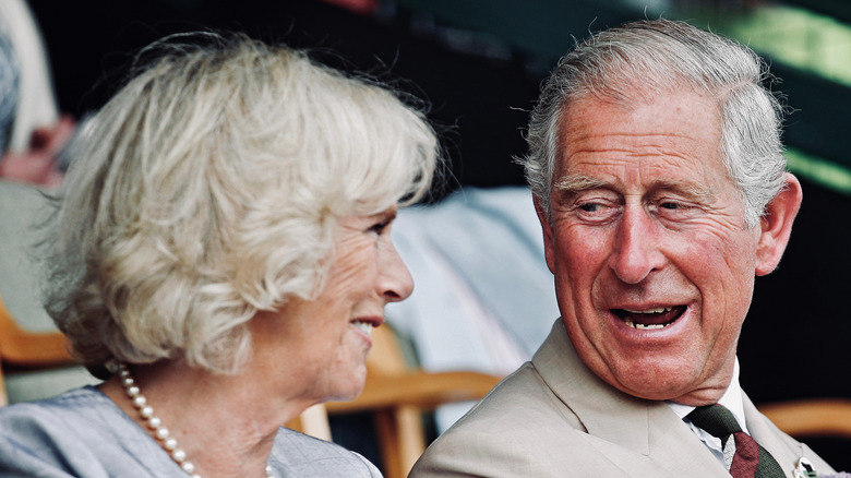 King Charles laughing next to Camilla Parker Bowles