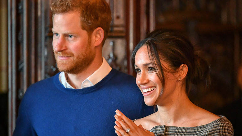 Meghan Markle claps while Prince Harry looks on