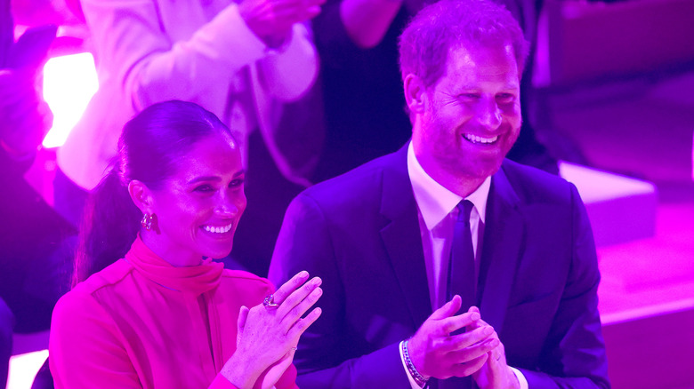 Meghan Markle and Prince Harry sitting smiling and clapping