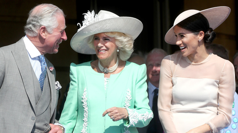 King Charles, Queen Camilla, and Meghan Markle smiling