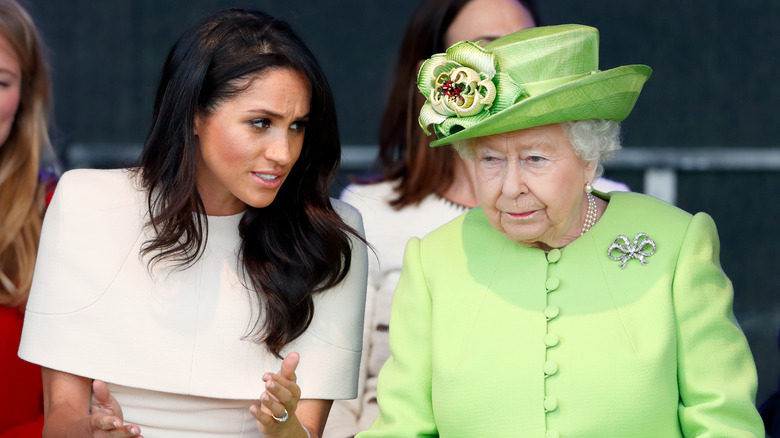 Queen Elizabeth looking grumpy while Meghan Markle talks