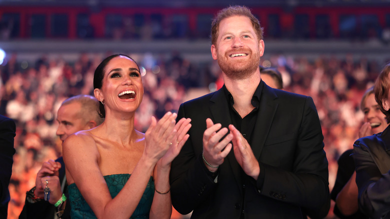 Meghan Markle and Prince Harry smiling and clapping