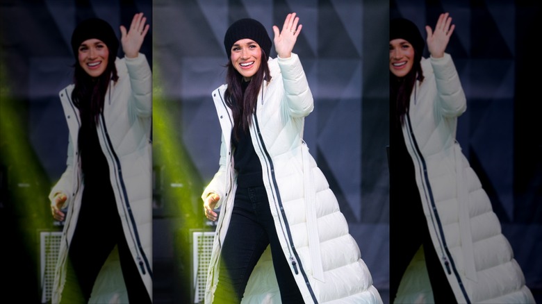 Meghan Markle waving in a white puffer coat at the 2025 Invictus Games