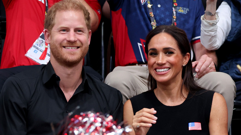 Prince Harry and Meghan Markle smiling in bleachers at the Invictus Games