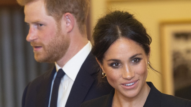 Closeup of Meghan Markle while Prince Harry stands behind her